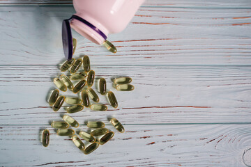 Pills sprinkled from a bottle on a wooden background vitamins and omega 3 for immunity