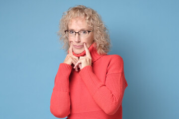 Caucasian senior woman tries to pretend she is happy in front of people. Fake smile concept.