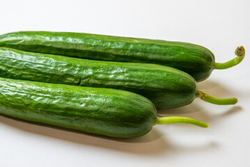 three green fresh cucumbers on a white background