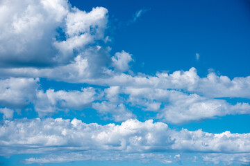 Naklejka na ściany i meble White heap clouds in the blue sky. Cloudscape over horizon. Heaven