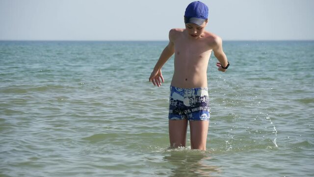Happy boy jumping in the Black Sea waters on a sunny day in summer in slo-mo