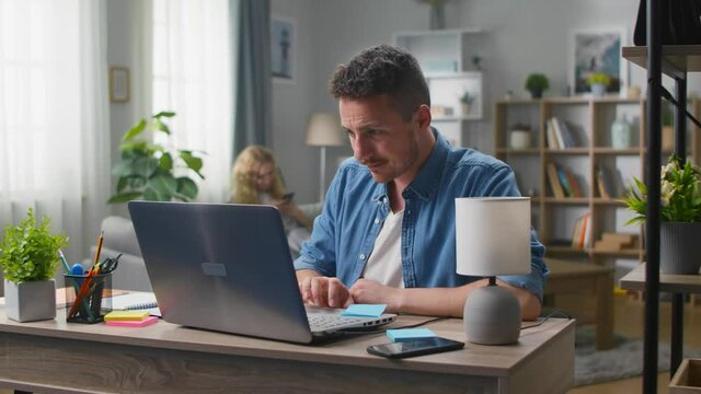 Young designer working on a laptop at home in the living room