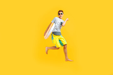 Fototapeta na wymiar happy excited teenager in sunglasses and a summer hat, having fun and jumping, holding an inflatable ring on a yellow background