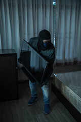 Robber in black mask stealing flat