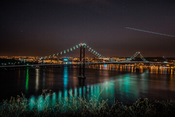 night photo of a bridge with a reflection in the river.