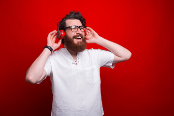 Photo of bearded guy listening music over red background