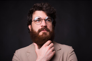 Close up portrait of bearded man wearing eyeglasses and looking away