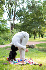 woman doing yoga exercise and relax with sportswear in green park at summer