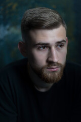 bearded guy portrait of a bearded young guy of twenty-five years old, in black clothes, on a dark background. Studio portrait on black.