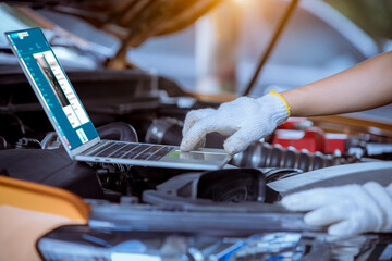 Close up hand car mechanic repairs and check car problem system by laptop  for maintenance and...