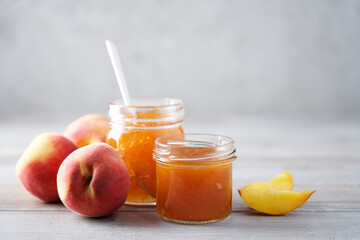 Peach jam in glass jar. Close-up view. Gray background