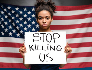 Black woman holding placard STOP KILLING US