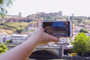 Woman hand and mobile phone, video and photo shooting scene, tourist and traveler take photo and video of old town of Tbilisi