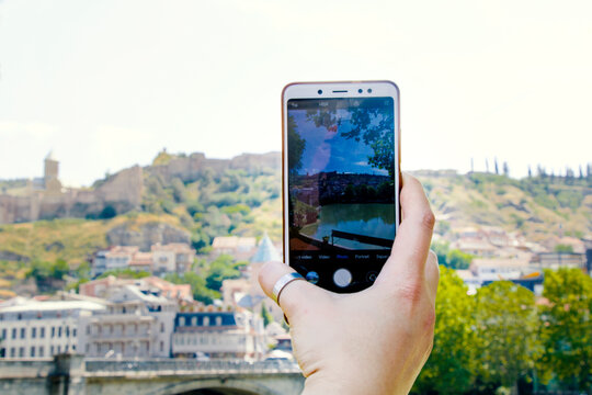 Woman hand and mobile phone, video and photo shooting scene, tourist and traveler take photo and video of old town of Tbilisi