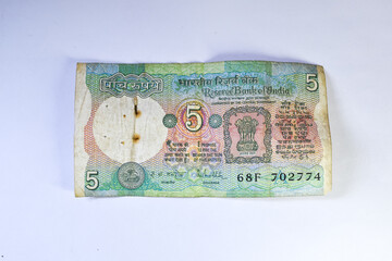 Old 5 rupees Indian currency note on white background.