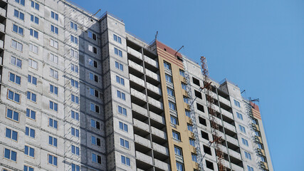 Large construction site on a background of blue sky. Brick, panel apartment building. Industrial theme for design