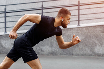 Fototapeta premium Sport man starting running. Young man jogging. Runner man running fast in city background. Workout, lifestyle concept. Athlete on the start.