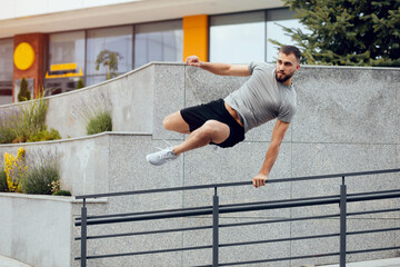 Handsome young athlete jumping over the fence. Full of energy. Full length of handsome young man in...