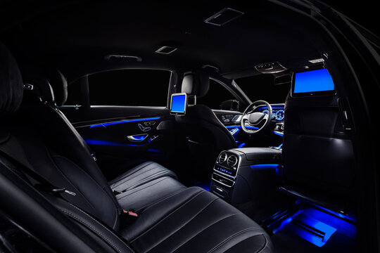 Car interior with comfortable black leather seats, displays and blue ambient light