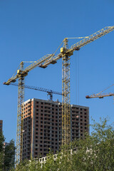 Multi-stage construction during the construction process with a yellow crane. Industrial background for design.