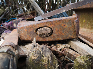 Broken rusty hammer head with rotten handle and some more rusty tools.