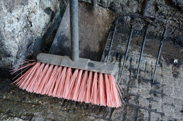 A vibrant pink bristled sweeping brush in a concrete cattle shed. Cold and dirty cattle shed...
