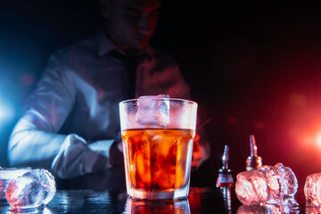 Expert bartender is making cocktail at night club. Barman preparing cocktails at the bar counter.