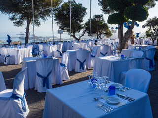 Mesas preparadas para celebracion entre arboles con la vista del puerto de Málaga al fondo