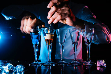 Barman preparing cocktail shots at the bar counter. Barman mixing drinks at the night club.