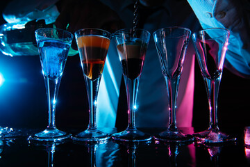 Barman preparing cocktail shots at the bar counter. Barman mixing drinks at the night club.