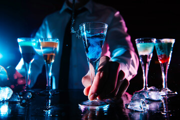 Barman preparing cocktail shots at the bar counter. Barman mixing drinks at the night club.