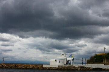 A church next to the sea, under a cloudy sky