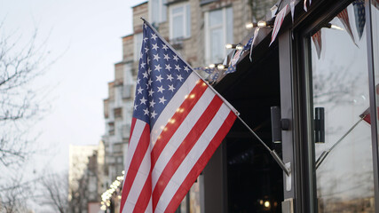 American flag on a building near the road against the background of the city. USA Symbol of power for Independence Day. Urban Temma Nu York. Stock photo