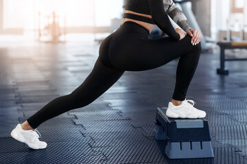 Closeup of fit woman stretching with help of step platform at sports club