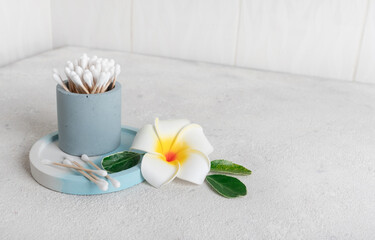 clean wooden and cotton ear buds environmental recyclable in the bathroom on a concrete background with a plumeria flower. Used in personal care, hygiene and makeup. Nobody.