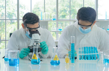 Asian Scientist working on blue test tube to analysis and develop vaccine of covid-19 virus in lab...