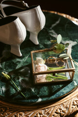 Elegant wedding accessories of an attractive bride. Wedding rings, shoes, bridal bouquet, floral arrangements, veil. Copy space for text. Background for greeting card or invitation.