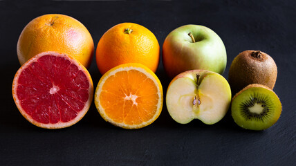 Fresh fruit, orange, apple, kiwi, grapefruit on black