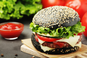 A black burger with vegetables and beef meat