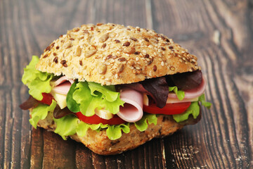 A sandwich with whole grain bread, ham and vegetables