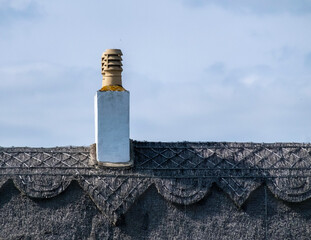 A thatched cottage roof with chimney