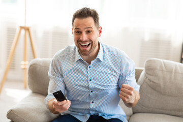 Emotional handsome man watching football game at home