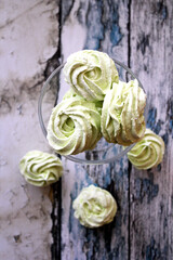 Mint zephyr on a glass goblet and on a wooden table. Light and airy dessert.