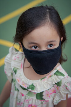 Portrait Of Toddler Wearing Reusable Black Face Mask In Outdoor.