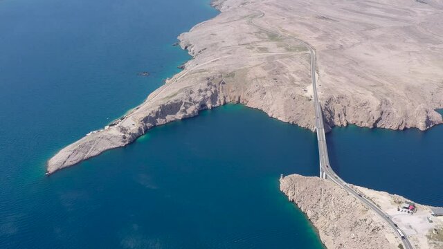 The Paski Most Arch bridge linking Pag island to the Croatian mainland with Ruine Fortica abandoned Fort left, Aerial hovering shot