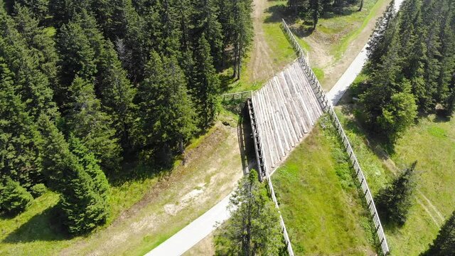 Vehicle bridge at Rogla Slovenia resort forest grounds with walking trail below, Aerial flyover shot