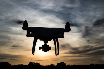 Silhouette of a drone in flight at sunset
