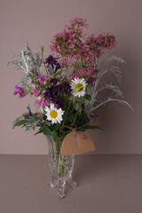 Bouquet of wild flowers in glass vase with blank tag