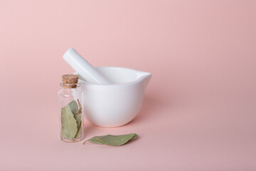 Dried bay leaves in glass jar,  white mortar on pink. Organic, nature.