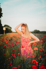 Frau im Sonnenuntergang auf Mohnwiese Im roten Kleid 